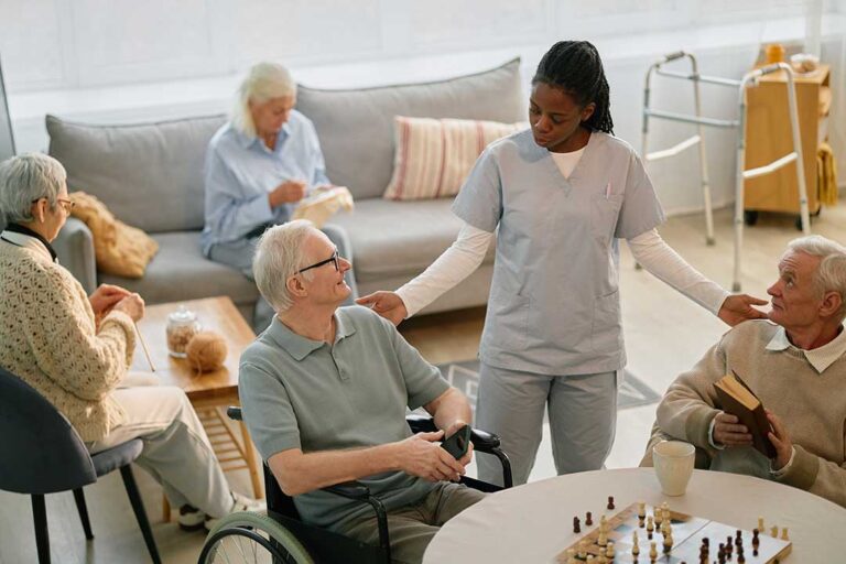 Seniors playing a board game together at a communal table in a bright, comfortable room.